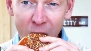 Close-up of McDonald’s CEO Chris Kempczinski taking a bite of the Big Arch burger during a promotional video.